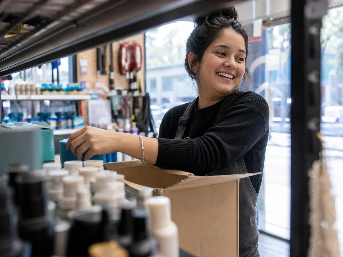 Vendeuse réassortissant un rayon, carton dans les bras